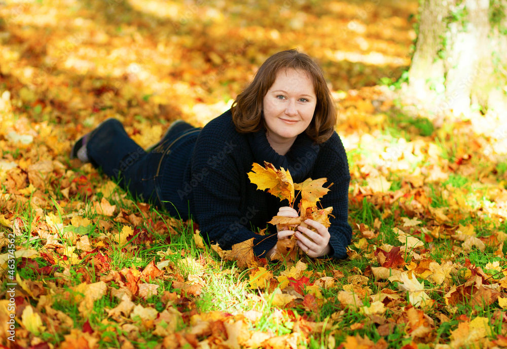 Happy girl lying on the ground in park on a fall day Happy girl lying on the ground in park on a fall day