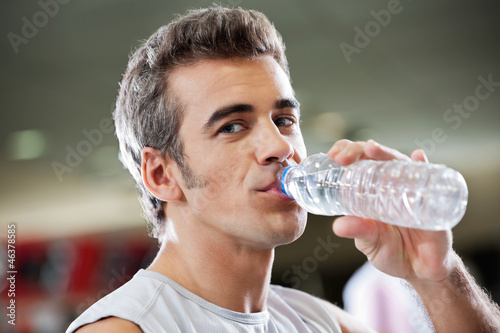 Man Drinking Water From Bottle At Health Club