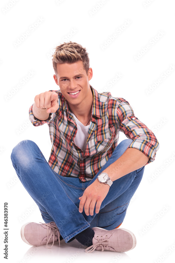 seated young man pointing at you seated young man pointing at you