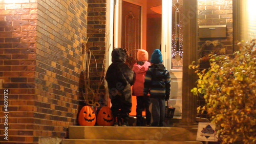 Three children  in Halloween costumes trick or treating