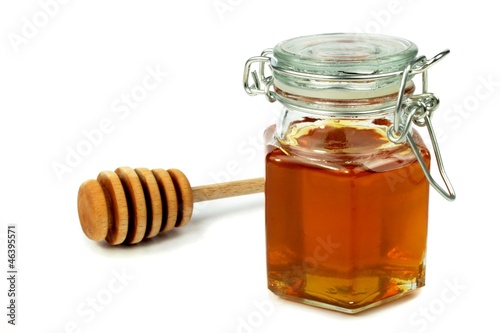 Honey in jar and dipper on white background.