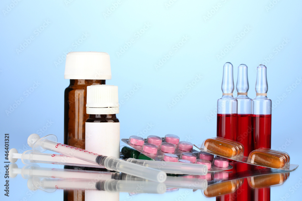 medical ampules, bottles, pills and syringes on blue background medical ampules, bottles, pills and syringes on blue background