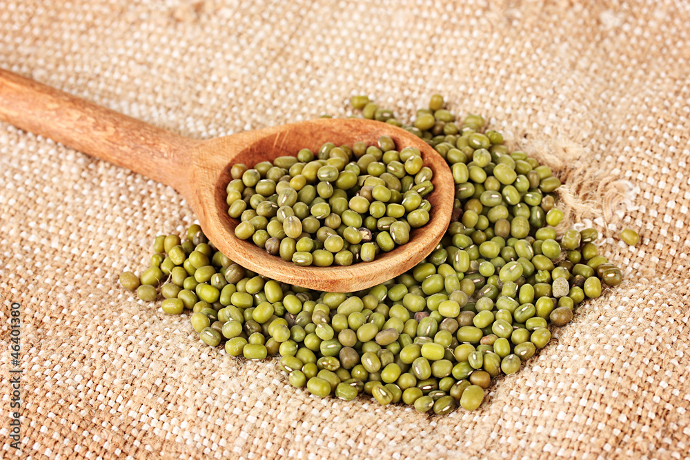 Mung beans over wooden spoon on sackcloth background Mung beans over wooden spoon on sackcloth background