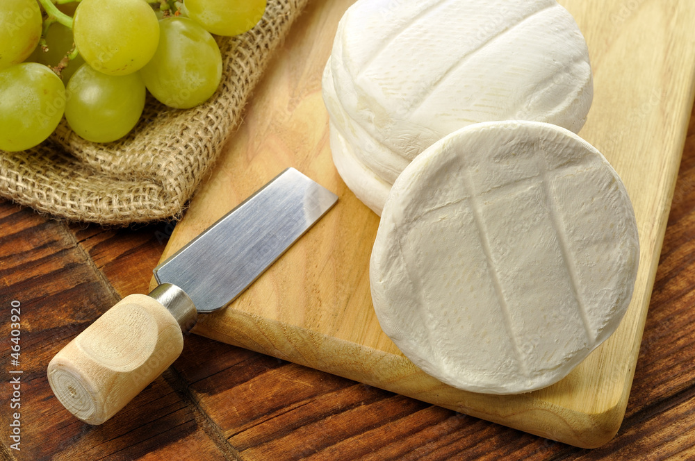 Italian tomino cheese on a wooden chopping board Italian tomino cheese on a wooden chopping board