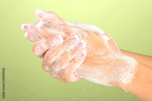 Woman s hands in soapsuds  on green background close-up