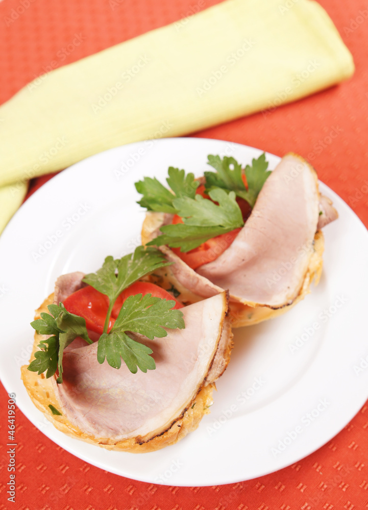Pair of sandwiches with ham and tomatoes on a plate