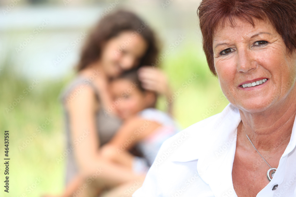Grandmother stood with daughter and grandson in background Grandmother stood with daughter and grandson in background