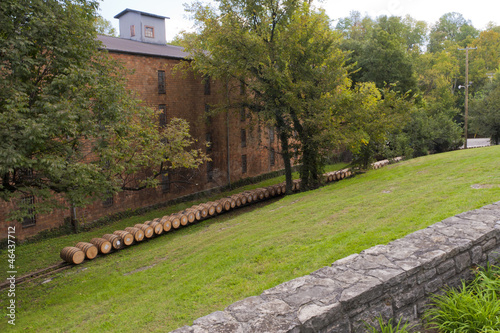 Line of whiskey barrels at distillery near warehouse photo