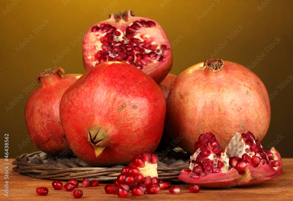 Ripe pomegranates on wicker cradle on yellow background Ripe pomegranates on wicker cradle on yellow background