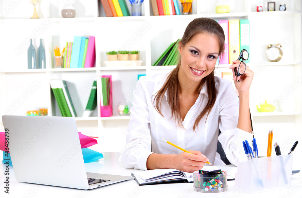 Young pretty business woman with notebook in office
