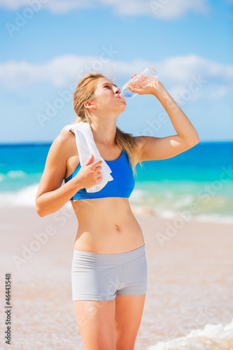 Beautiful Young Drinking Water after Beach Workout