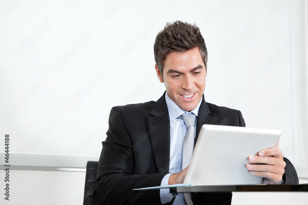 Young Businessman Using Digital Tablet In Office Young Businessman Using Digital Tablet In Office