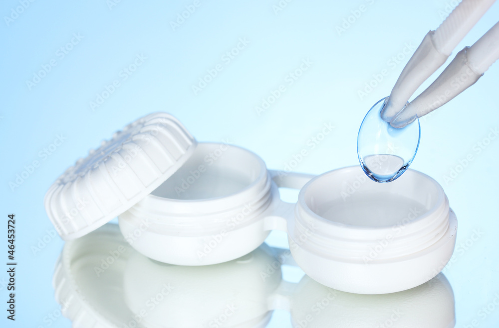 contact lenses in containers and tweezers on blue background contact lenses in containers and tweezers on blue background