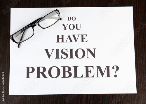 Eyesight test chart with glasses on wooden background close-up