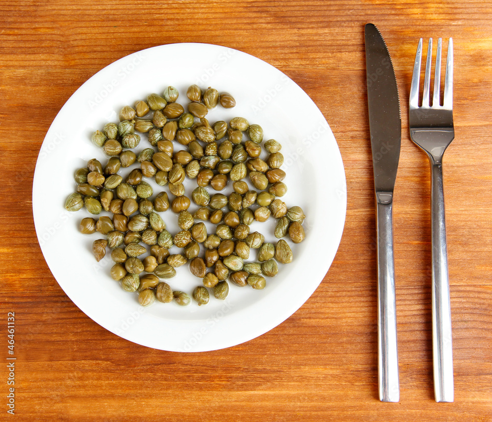 Capers in the plate on wooden background Capers in the plate on wooden background