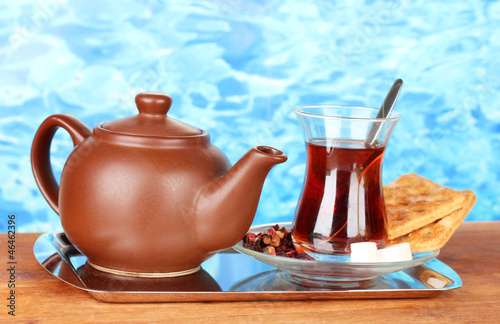 glass of Turkish tea and kettle on color background © Africa Studio