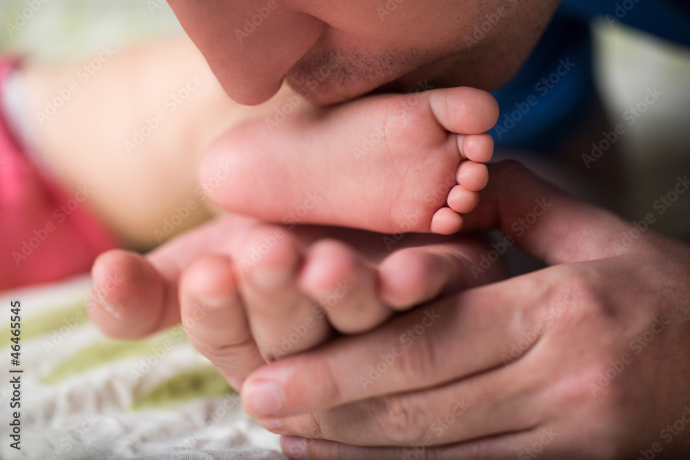 Father holding and kissing a sleeping baby foot Father holding and kissing a sleeping baby foot