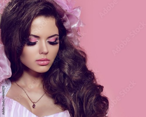 Beautiful young girl with curly hair and bright make-up. Jewelry