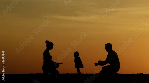 Silhouette of parents teaching their daughter walking