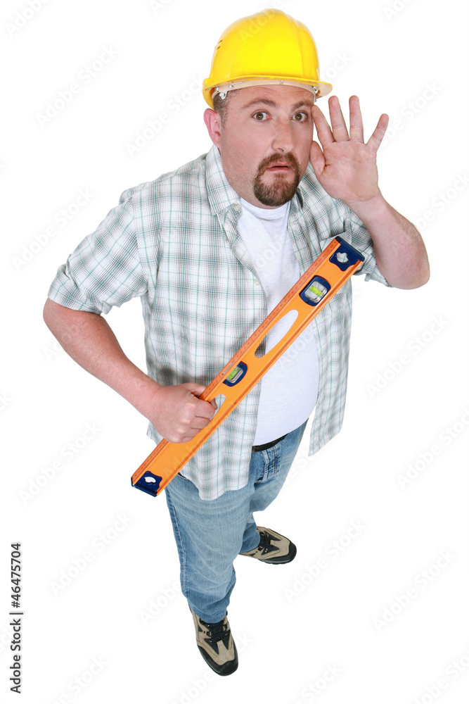 Builder with spirit-level holding hand to ear Builder with spirit-level holding hand to ear