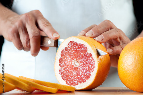 Senior woman slicing a grapefruit, horizontal shot