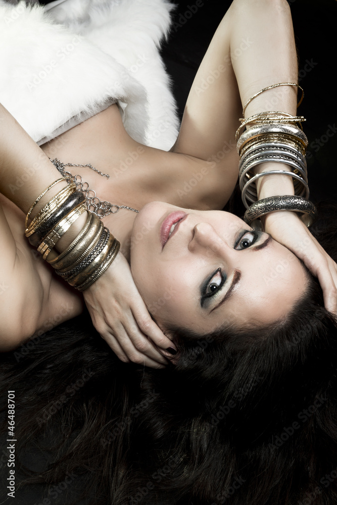 Fototapeta premium Woman lying and sensual with bracelets of gold and silver, green