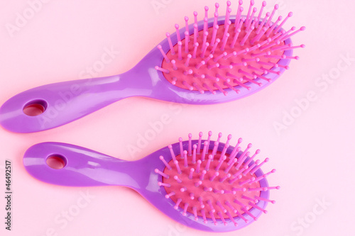 two purple hair brushes on pink background