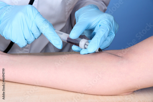 Nurse takes blood from the veins on blue background