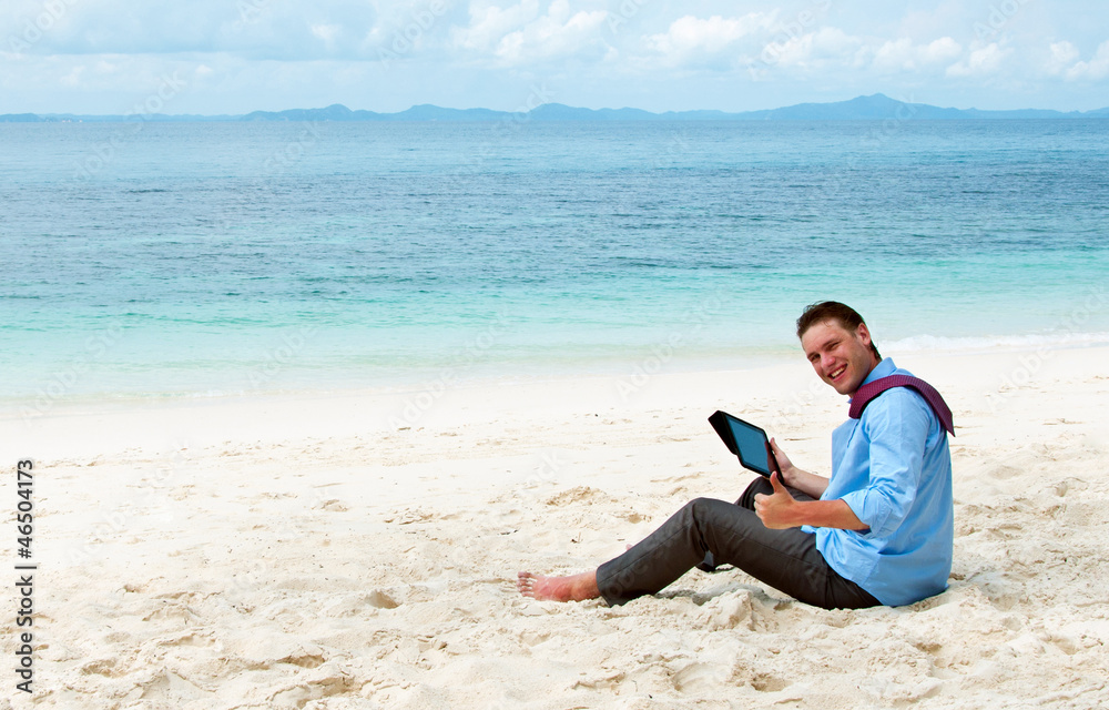Business man sitting and working on the beach with tablet comput
