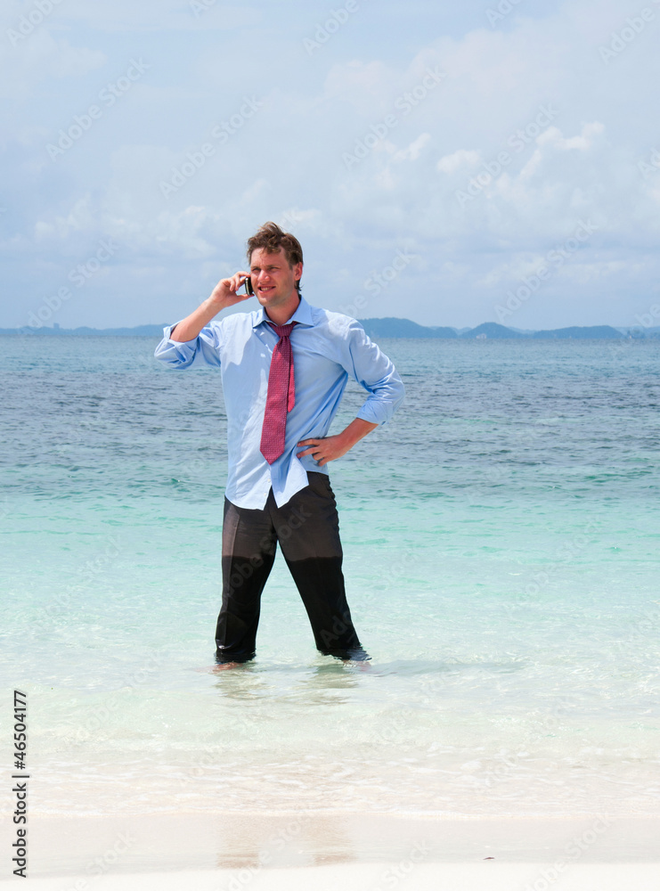 Business man calling by cell phone on the beach