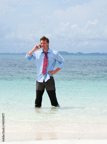 Business man calling by cell phone on the beach
