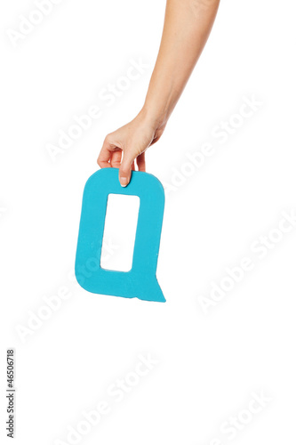 hand holding up the letter Q from the top