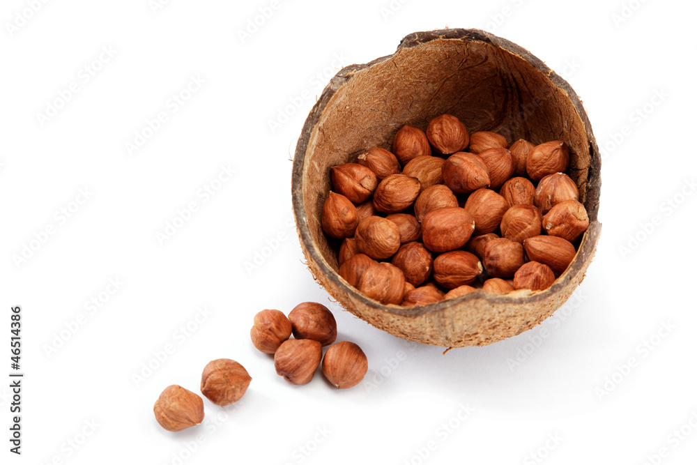 Hazelnuts in a coconut shell isolated on white background. Hazelnuts in a coconut shell isolated on white background.