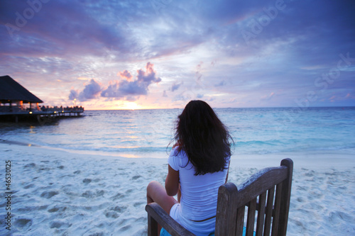 Woman sitting on beach chair at sunset photo