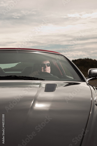 Senior good looking happy retired man driving his sports car.