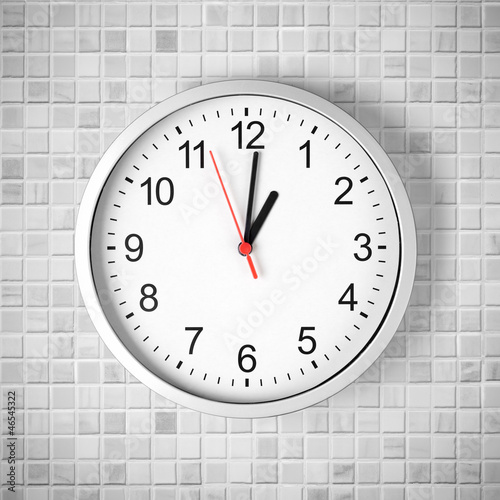 Simple clock or watch on white tile wall displaying one o'clock
