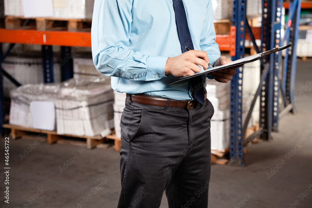 Supervisor Writing On Clipboard At Warehouse