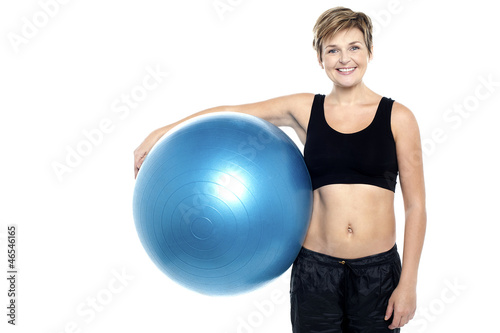 An attractive fit lady holding blue pilates ball