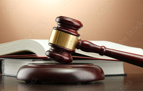 wooden gavel and books on wooden table,on brown background photo