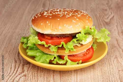 Big and tasty hamburger on plate on wooden table