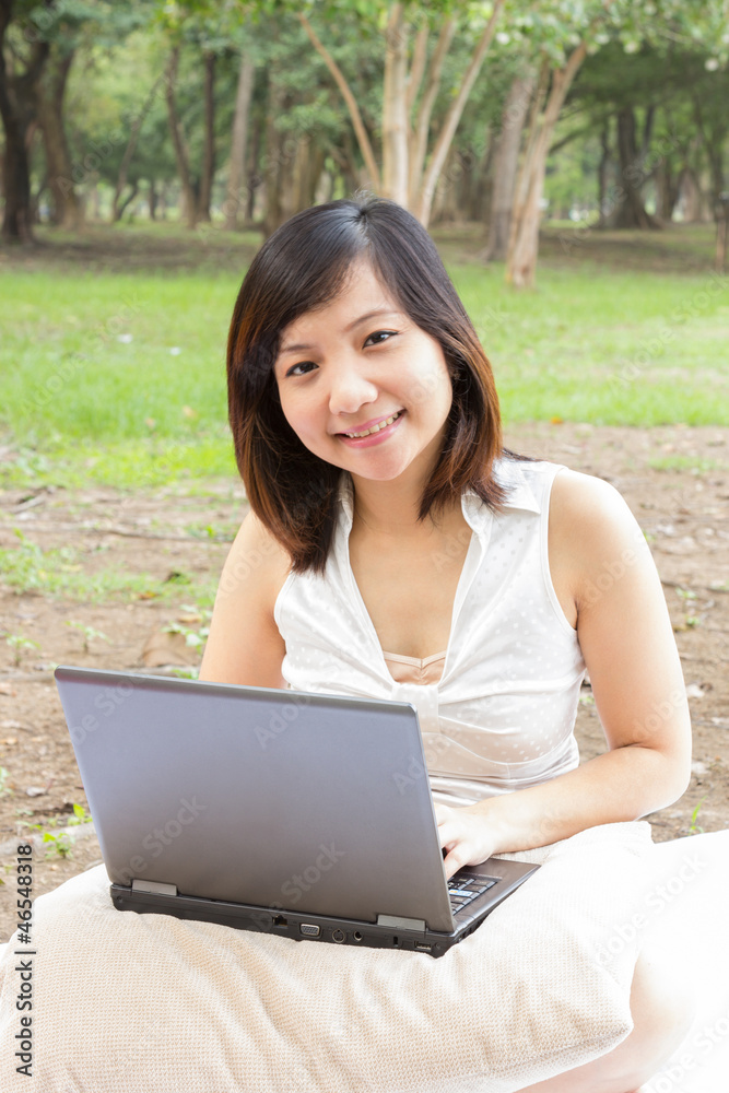 Asian woman smiling with laptop sitting at park Asian woman smiling with laptop sitting at park