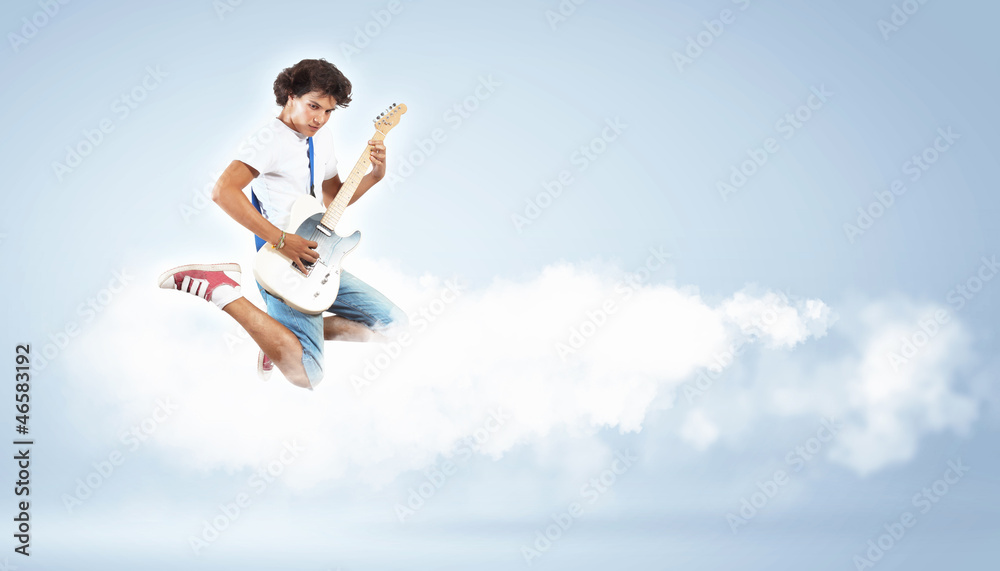 young man playing on electro guitar and jumping