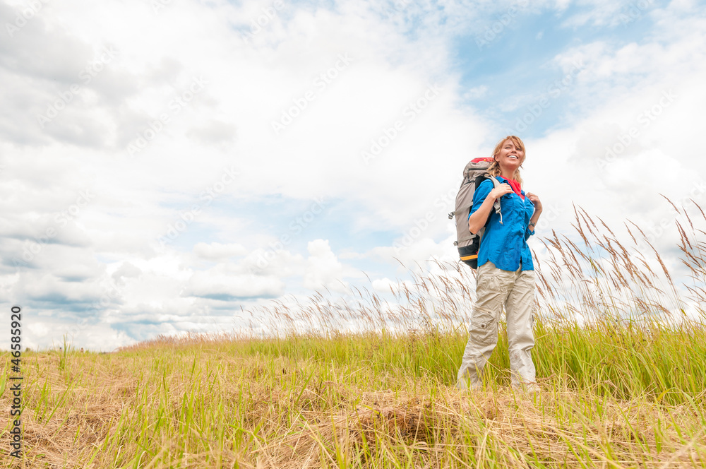 Young girl walking in meadow with backpack on.