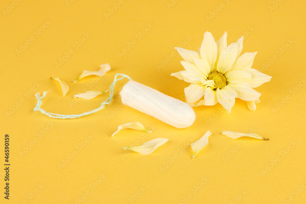 cotton tampon with yellow flower on orange background close-up