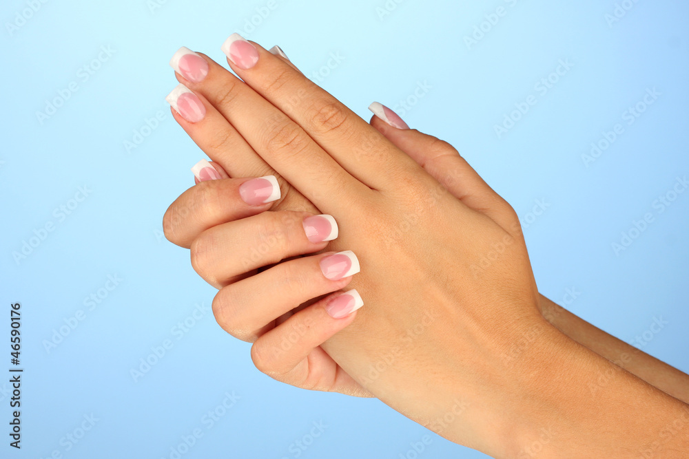 Beautiful woman's hands with french manicure on blue background Beautiful woman's hands with french manicure on blue background