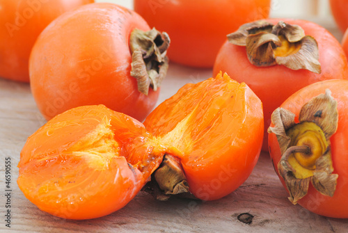 Tableau sur toile Close up fuyu persimmons fruits whole and cutted on white wood