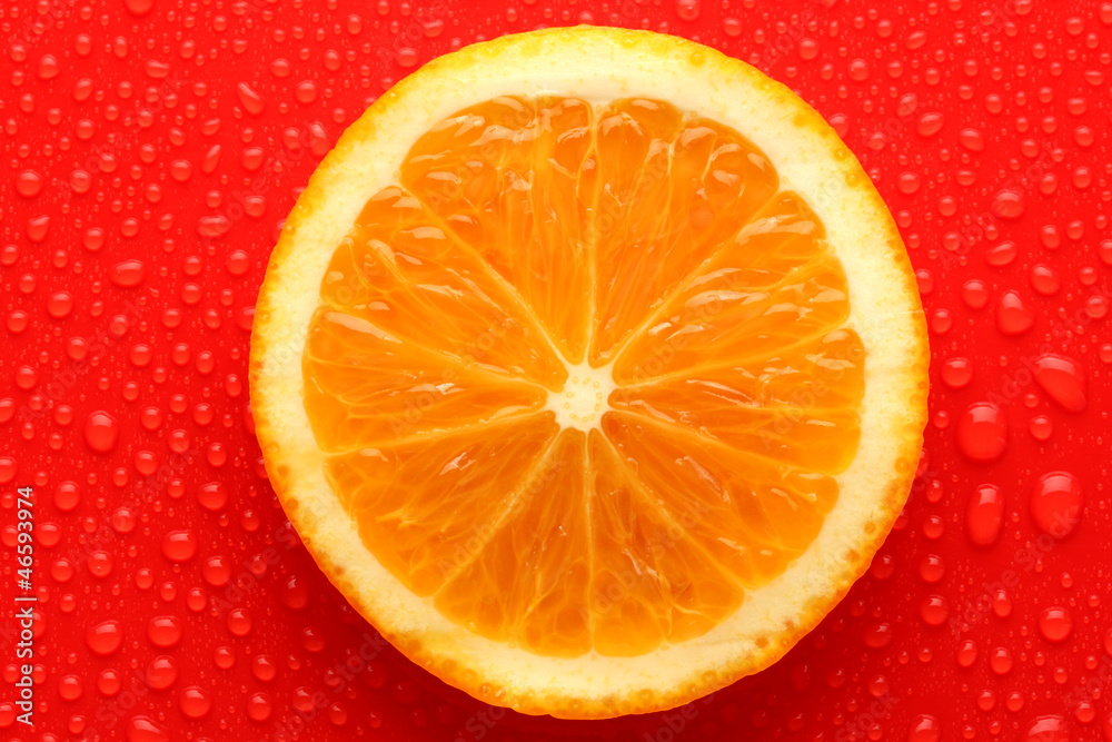 Slice of orange with drop on red background Slice of orange with drop on red background