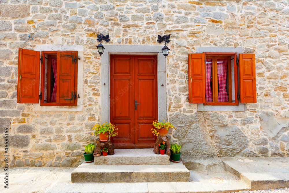 house with wooden windows and doors, surrounded in the stone wal house with wooden windows and doors, surrounded in the stone wal