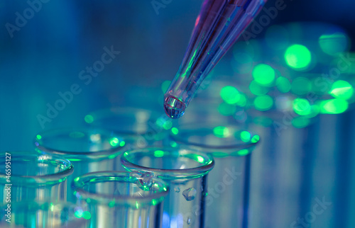 Pipette adding fluid to one of several test tubes photo