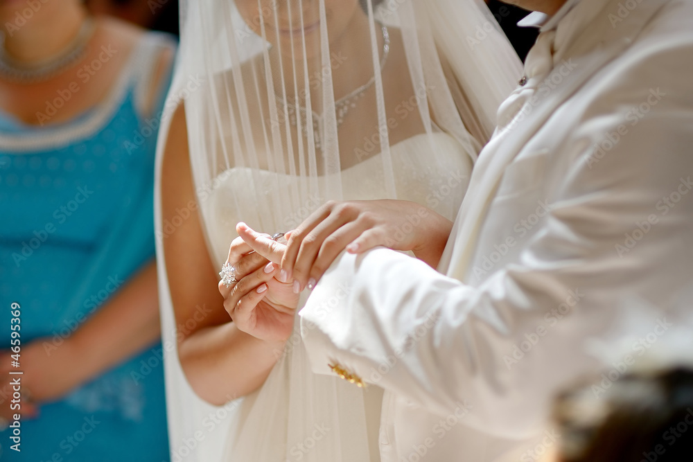 Bride putting the ring on groom's finger Bride putting the ring on groom's finger